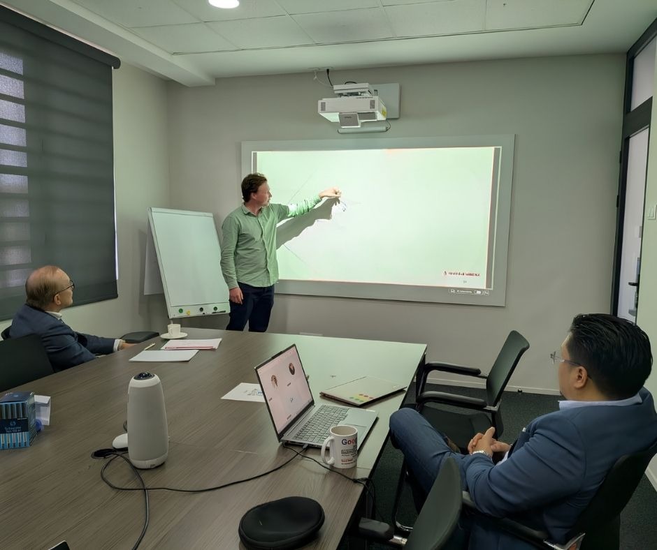 Riemer presentatie Een jonge man presenteert in een vergaderzaal voor 2 mannen met een laptop op tafel